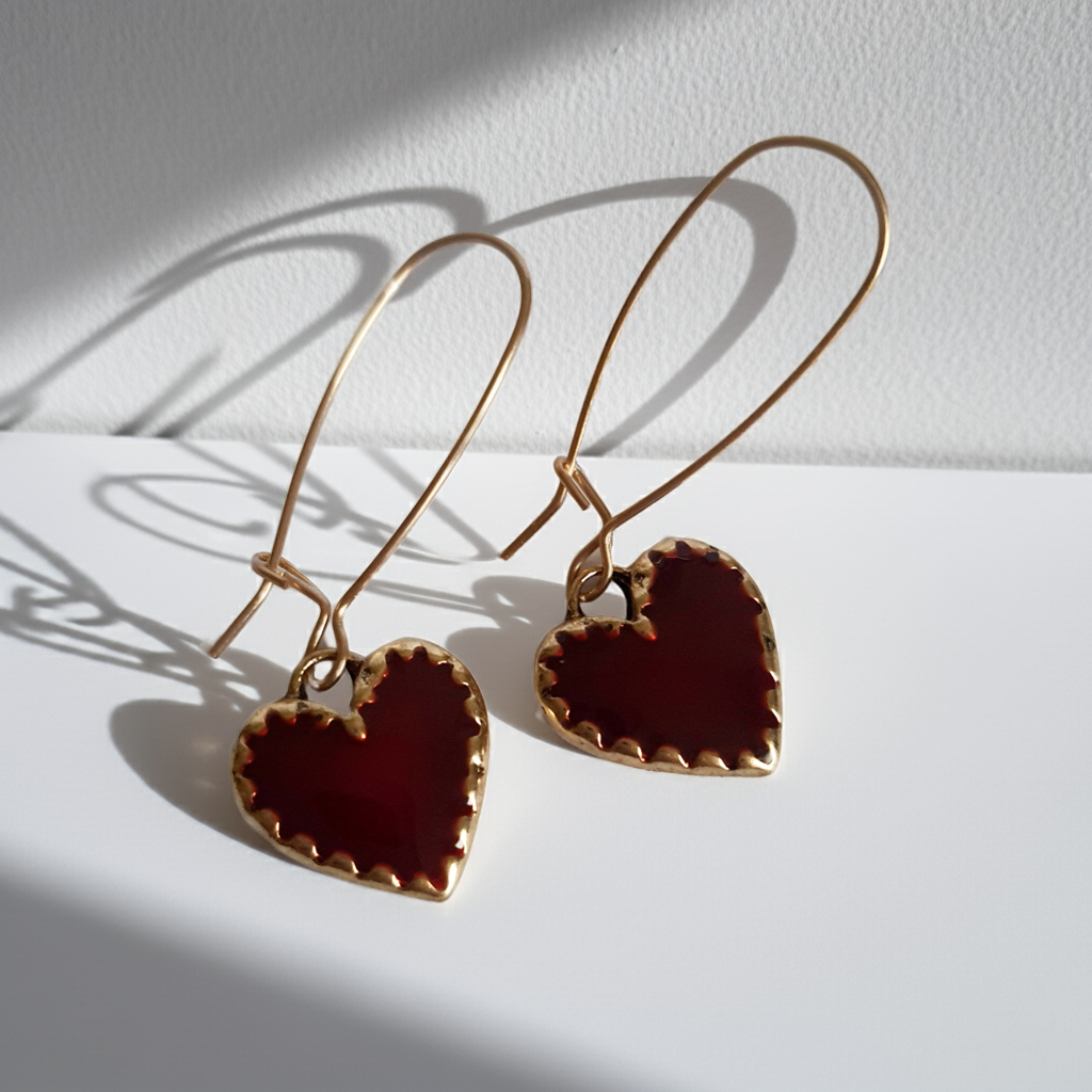 Kolczyki wiszące ze stali nierdzewnej w kolorze złota, z zawieszkami w kształcie czerwonych serc. Długość 5 cm. Styl romantyczny i elegancki. Rouge Bizu.