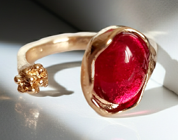 Złoty pierścionek z czerwonym syntetycznym kamieniem i drobnym kwiatowym detalem, romantyczny styl, stal nierdzewna, rozmiar 16 mm. Rouge Bizu.
