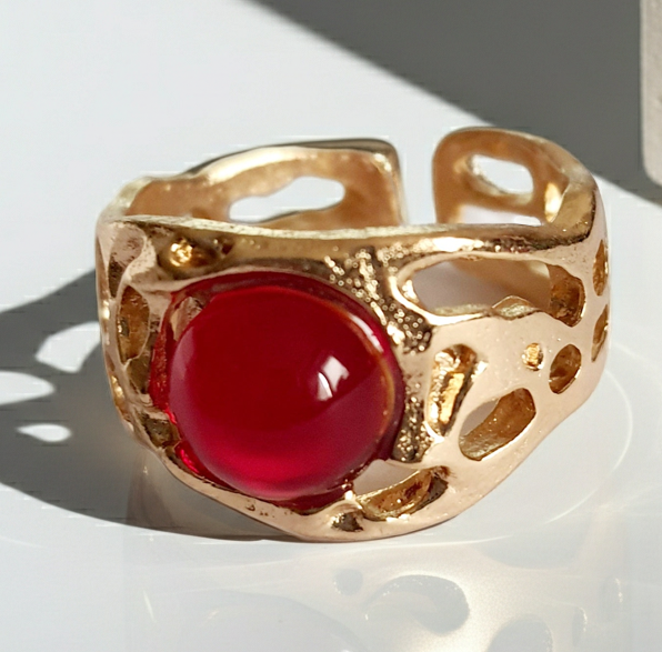 Złoty pierścionek artystyczny z czerwonym kaboszonem, stal nierdzewna, ażurowa forma, rozmiar 16 mm, elegancki i wyrazisty. Rouge Bizu.
