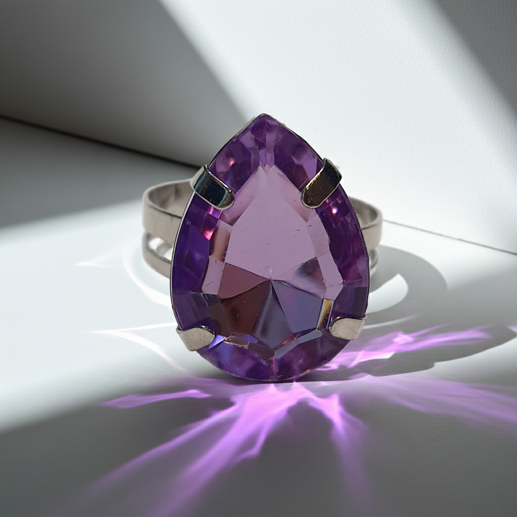 Srebrny pierścionek z dużym fioletowym kamieniem w kształcie łezki, metal, szlifowany kamień o głębokim połysku, elegancki styl, regulowany rozmiar, Rouge Bizu.