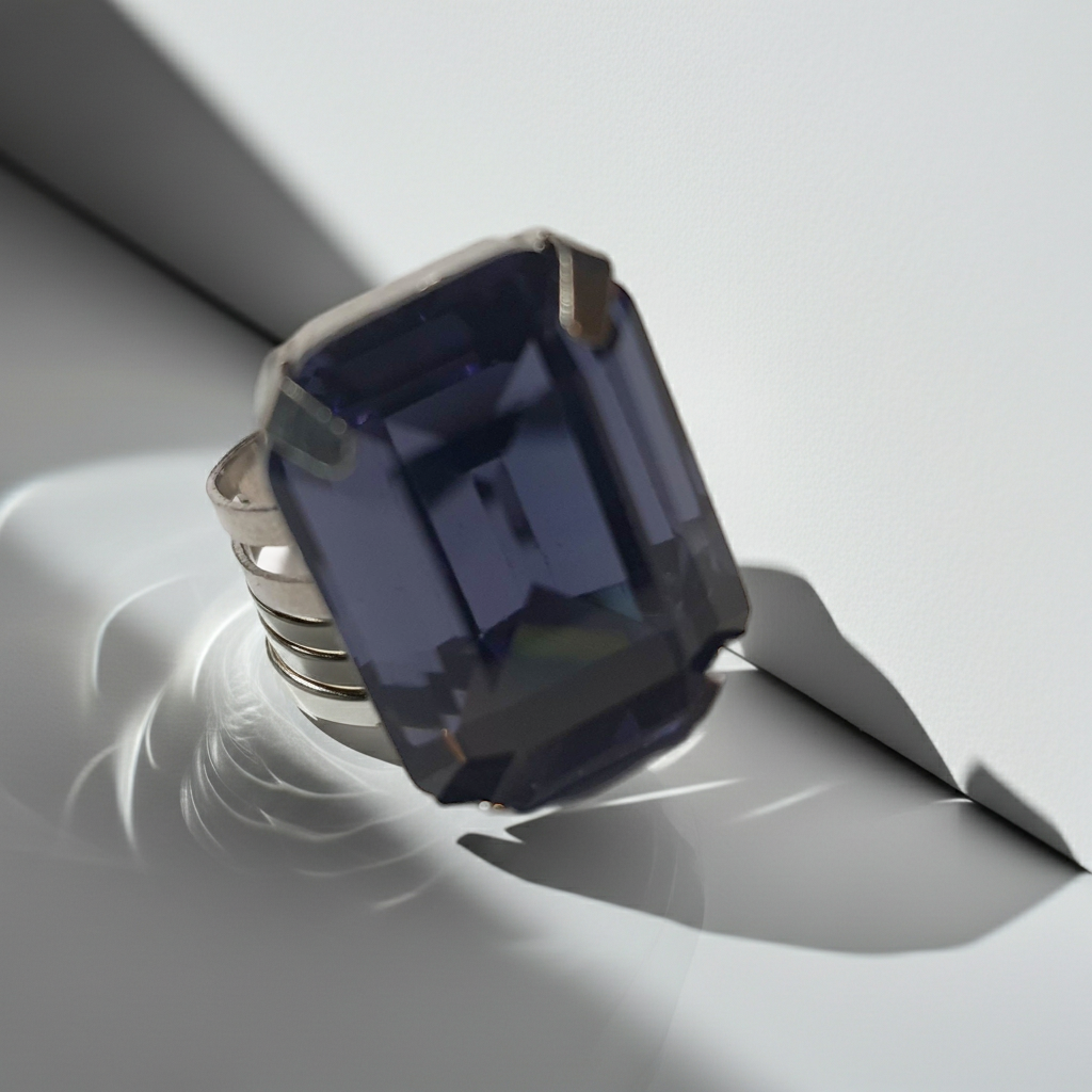 Srebrny pierścionek z prostokątnym fioletowym kamieniem w eleganckim szlifie, metal, chłodny odcień, klasyczny styl, regulowany rozmiar, Rouge Bizu.