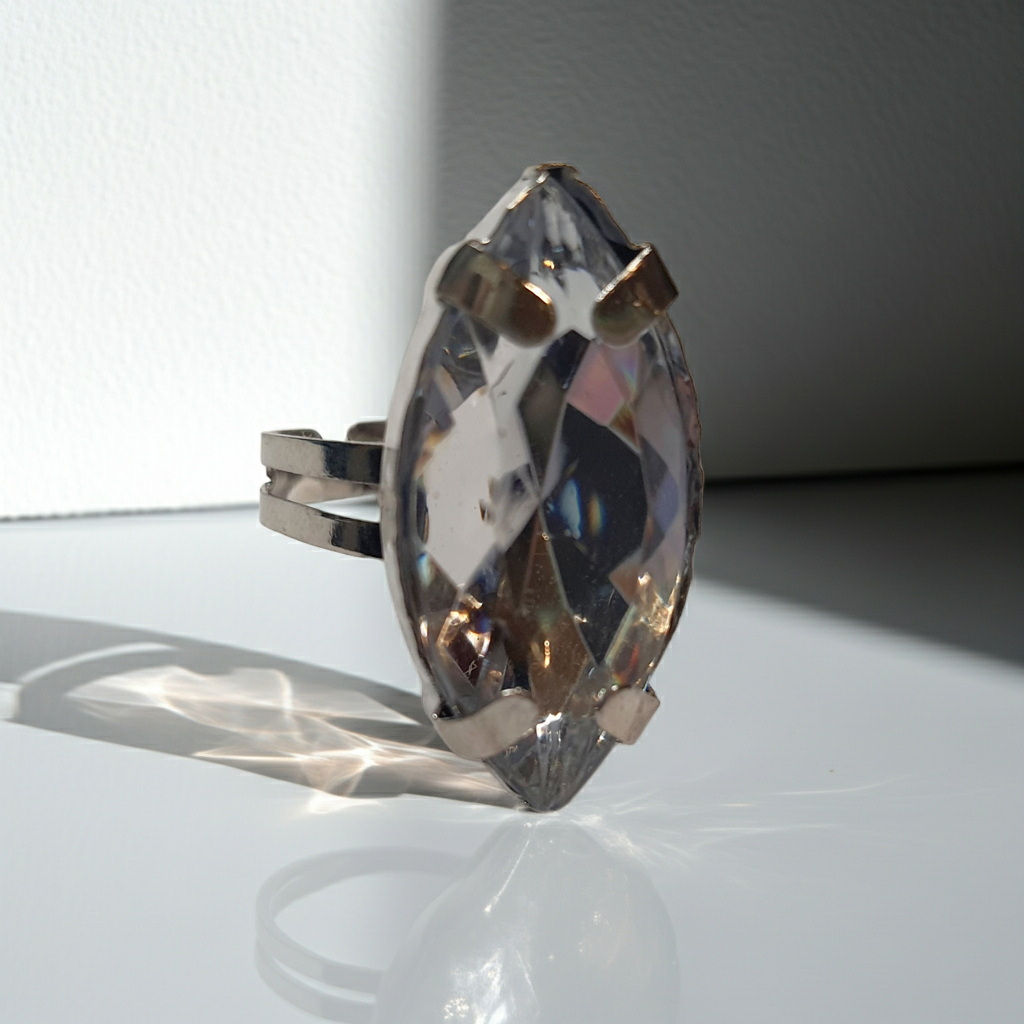 Srebrny pierścionek z dużym transparentnym kamieniem w kształcie łezki, metal, szlifowany kamień o lśniącym połysku, styl glamour, regulowany rozmiar, Rouge Bizu.
