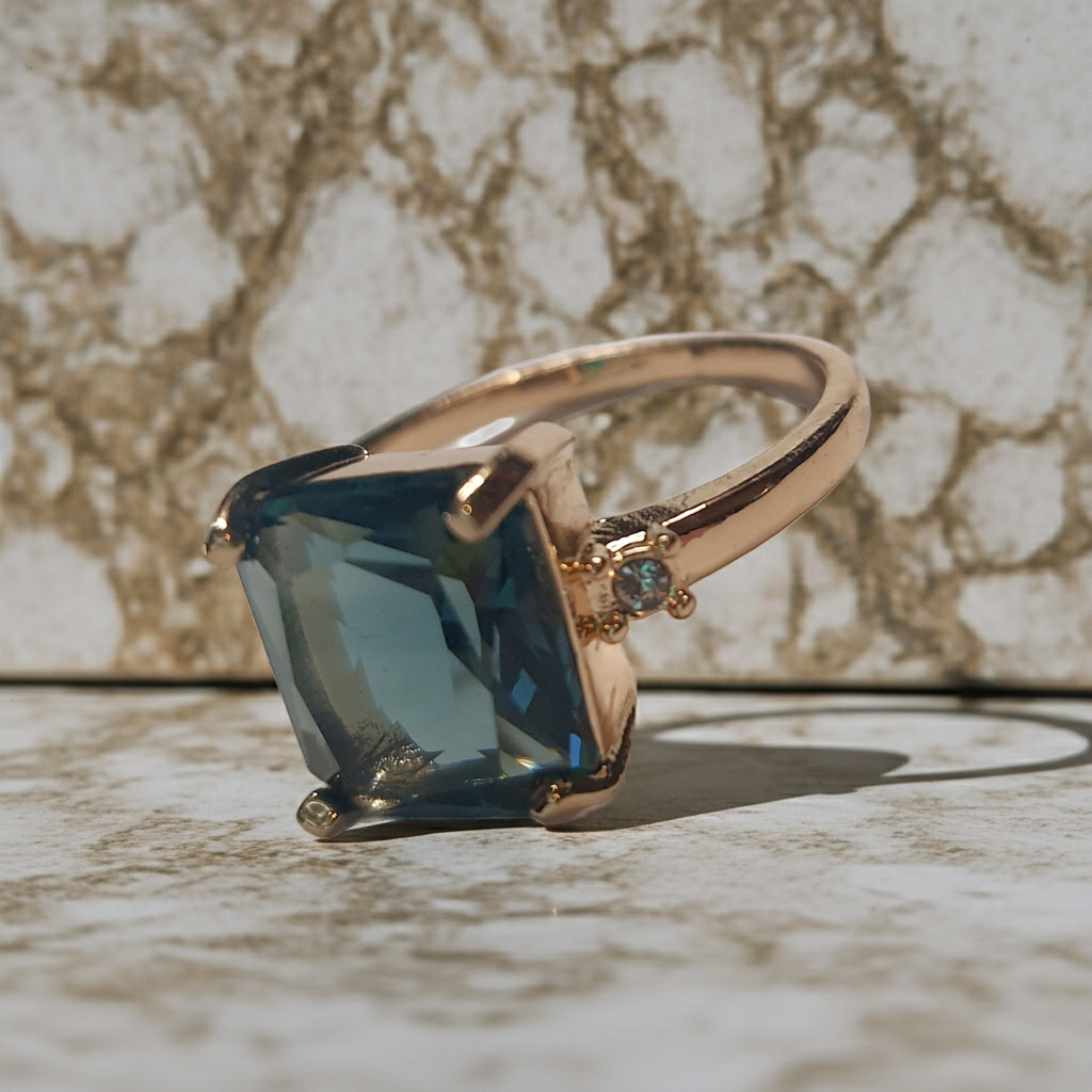 Złoty pierścionek ze stali nierdzewnej z prostokątnym szafirowym kamieniem i drobnymi cyrkoniami po bokach w stylu klasycznym glamour. Rozmiar 19 mm. stal chirurgiczna, stal nierdzewna, wodoodporne, hipoalergiczne, jakość premium, RougeBizu.