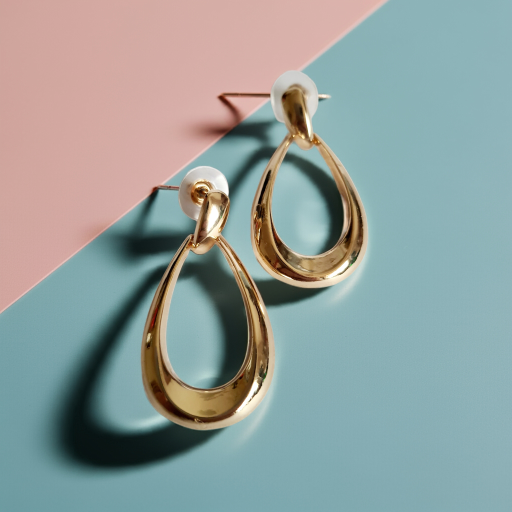 Złote kolczyki ze stali nierdzewnej w kształcie minimalistycznych kropli, eleganckie i ponadczasowe, długość 4 cm. Rouge Bizu.