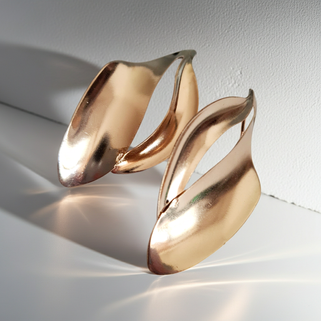 Kolczyki ze stali nierdzewnej w kolorze złotym o rzeźbiarskim kształcie fal. Długość 7 cm, na wkrętki. Eleganckie, lekkie i nowoczesne. Rouge Bizu.
