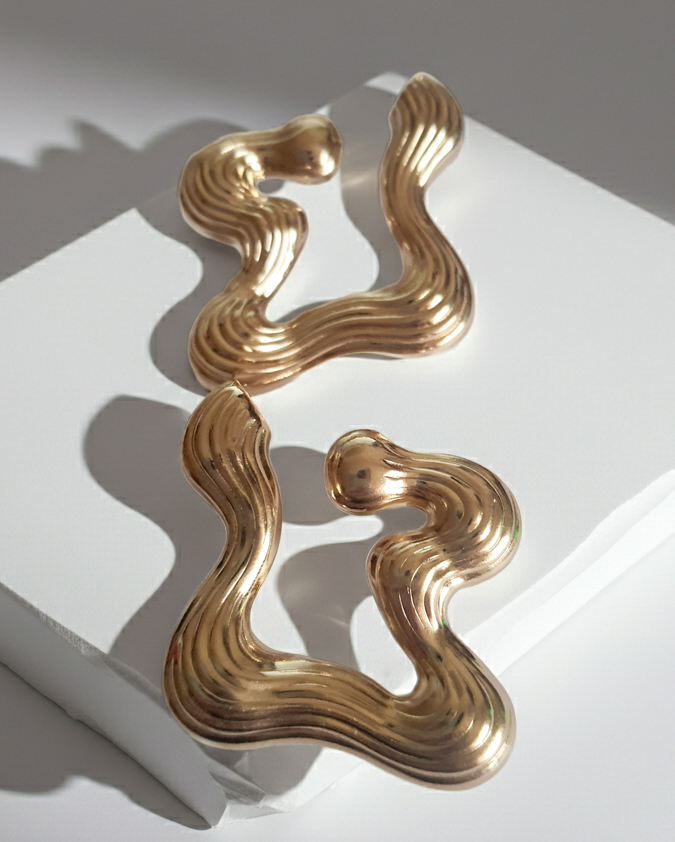 Złote kolczyki falujące o artystycznej, nieregularnej formie, eleganckie i nowoczesne. Stal nierdzewna, długość 5 cm. Rouge Bizu.