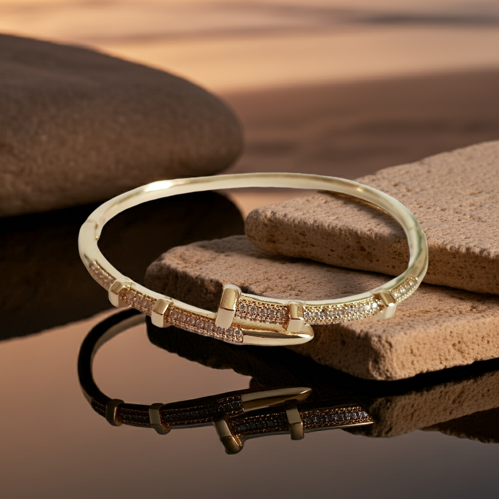 Złota bransoletka sztywna o średnicy 6 cm, zdobiona białymi cyrkoniami, nowoczesny elegancki design, stal nierdzewna. Rouge Bizu.
