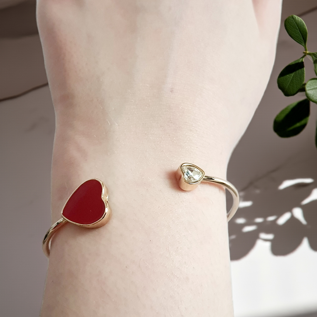 Sztywna złota bransoletka ze stali nierdzewnej z czerwonym sercem i bezbarwnym kryształem, minimalistyczny design. Rouge Bizu.
