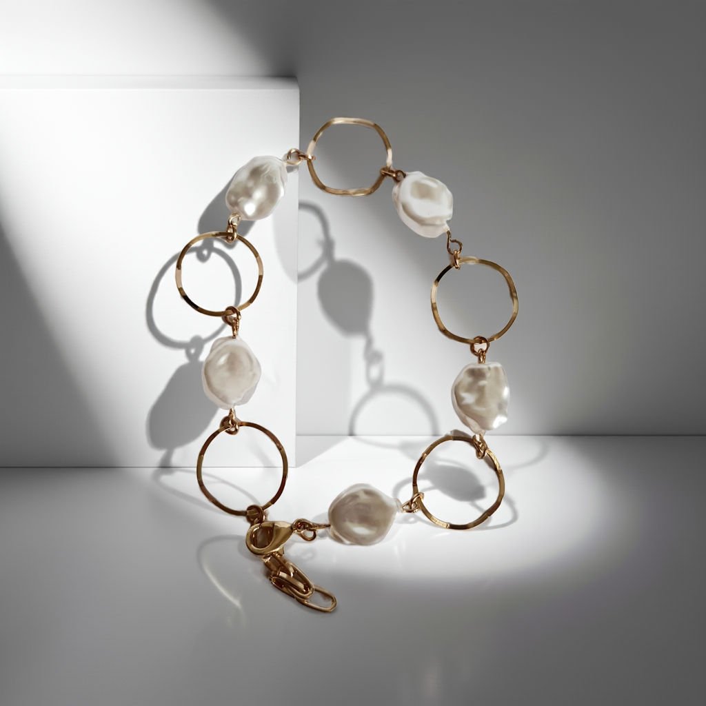 Bransoletka ze stali nierdzewnej w kolorze złota, z nieregularnymi białymi perłami i złotymi kołami. Regulowana długość 22–26 cm. Styl elegancki i minimalistyczny. Rouge Bizu.