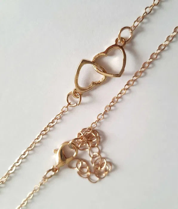 Złoty łańcuszek celebrytka z zawieszką z dwóch przeplatających się serduszek, długość 47–53 cm, wykonany ze stali chirurgicznej.

