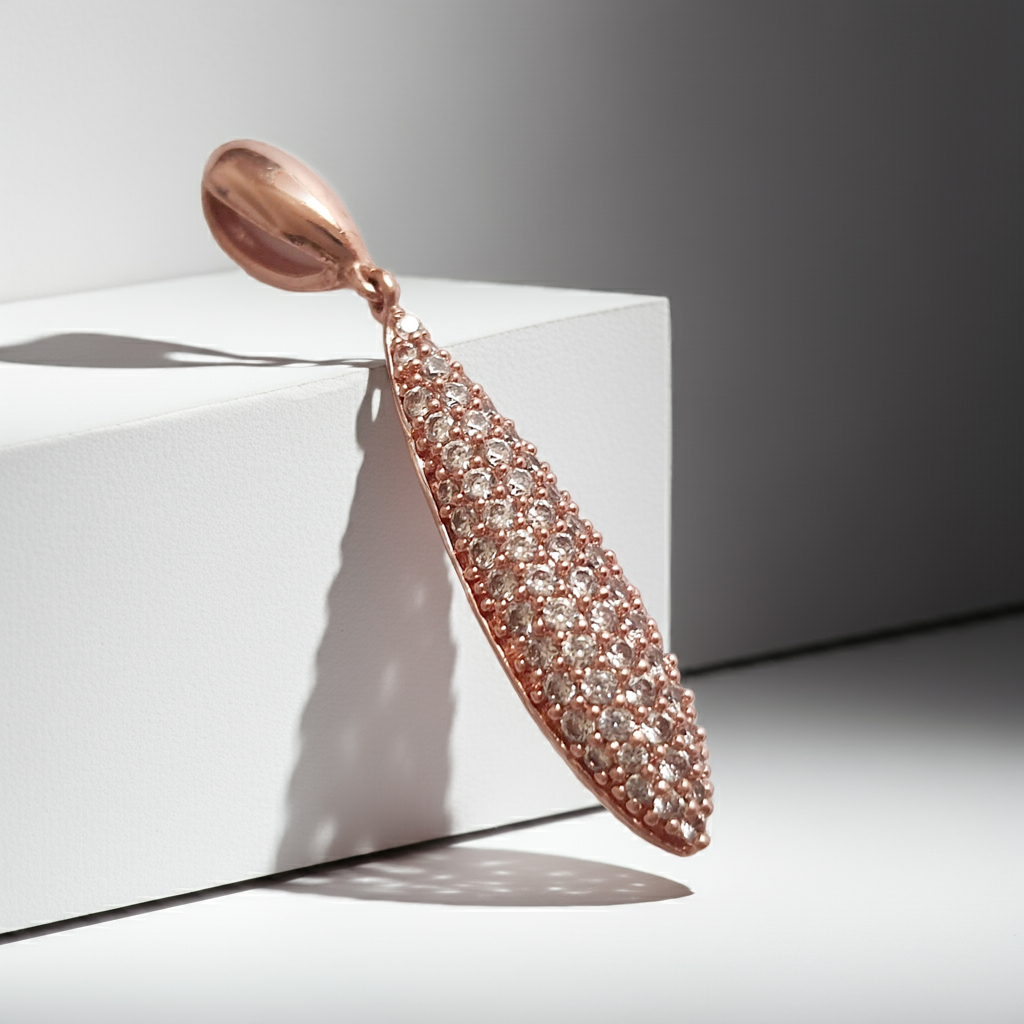 Wisiorek ze stali chirurgicznej w kolorze różowego złota, długość 4 cm, w kształcie kropli wysadzanej drobnymi cyrkoniami. Elegancki połysk, nowoczesny glamour. Rouge Bizu.

