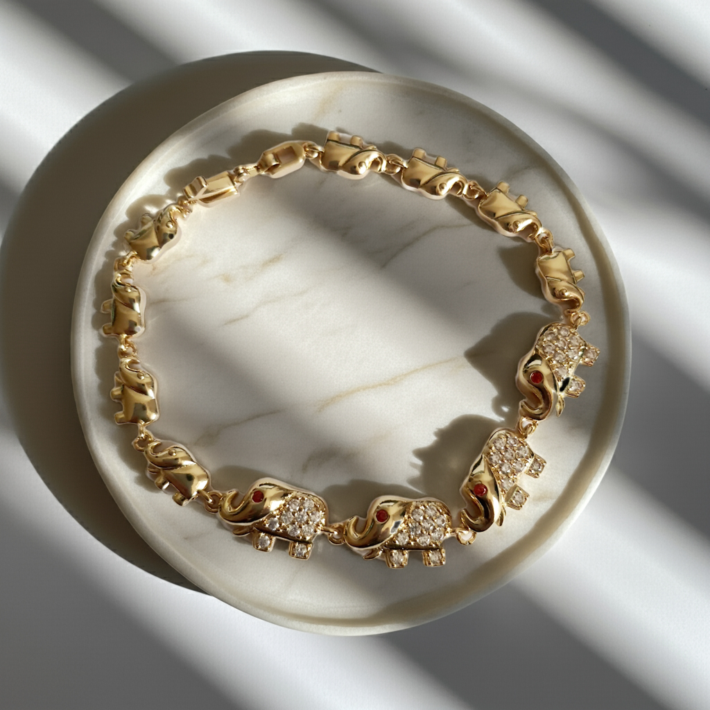 Bransoletka ze stali nierdzewnej w kolorze złota z motywem słoni, zdobiona cyrkoniami i czerwonymi oczkami. Symbol szczęścia, długość 20 cm. Rouge Bizu.